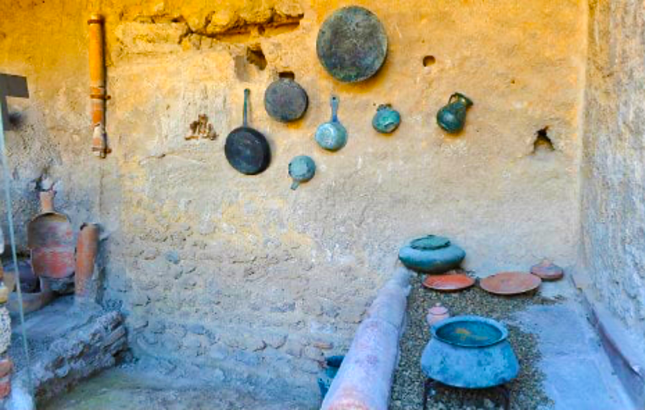 Reconstructed pompeiian kitchen with open fire trough on the right.