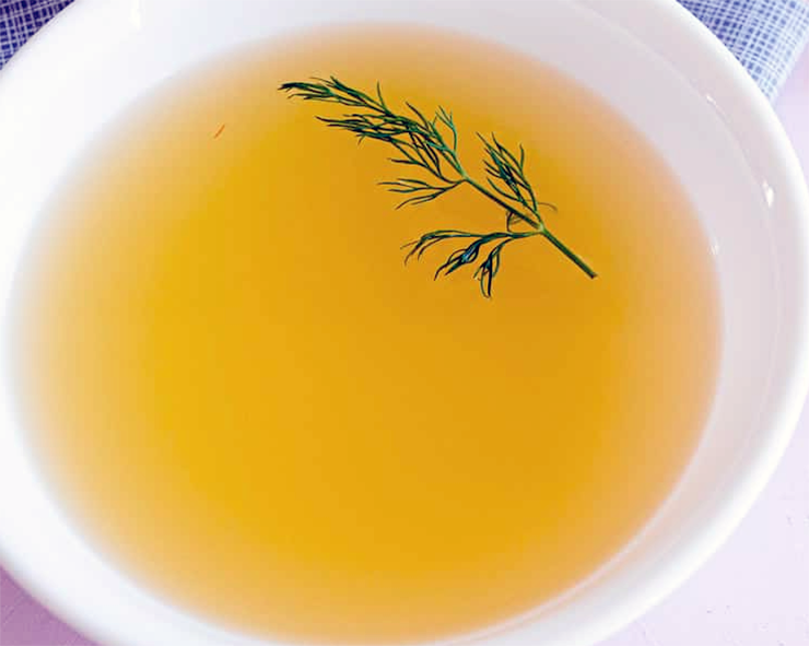 Clear court bouillon in a bowl with sprig of dill