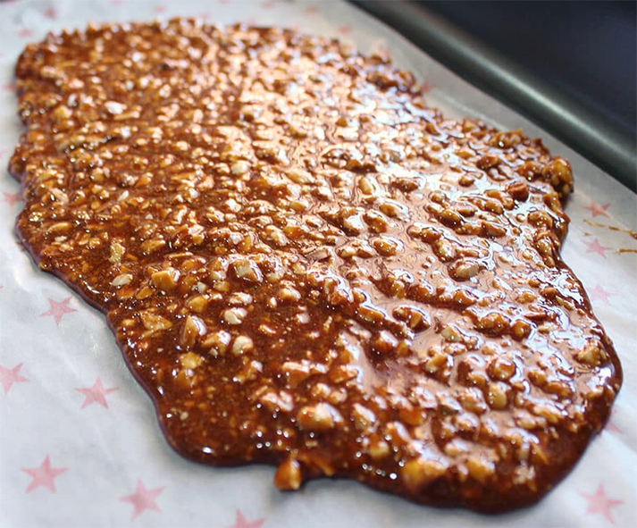 sheet of almond praline on greaseproof paper in a roasting tin