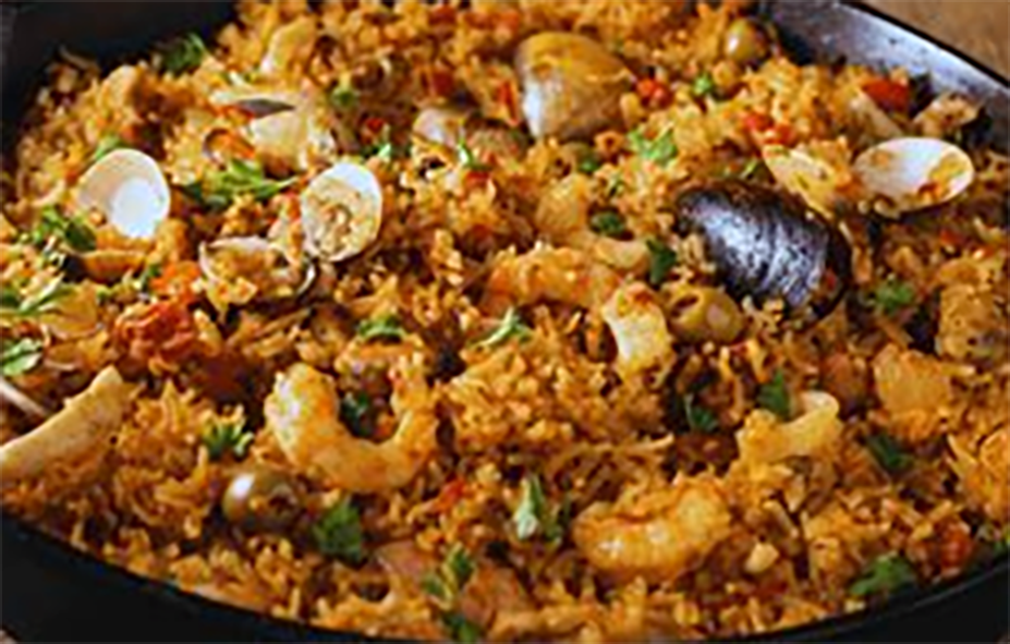 rice with peas, pork, mussels and crayfish in a cast iron pan