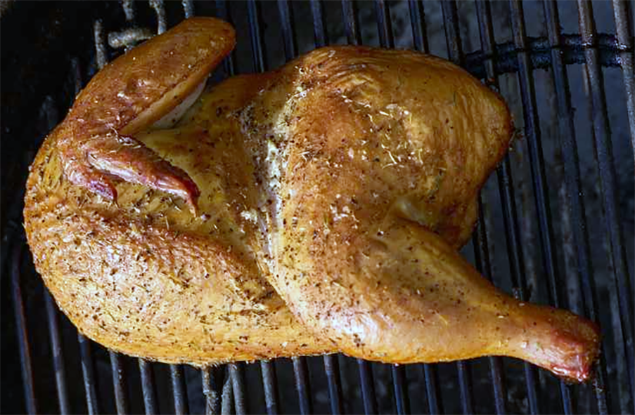 spiced chicken half cooking on a barbecue