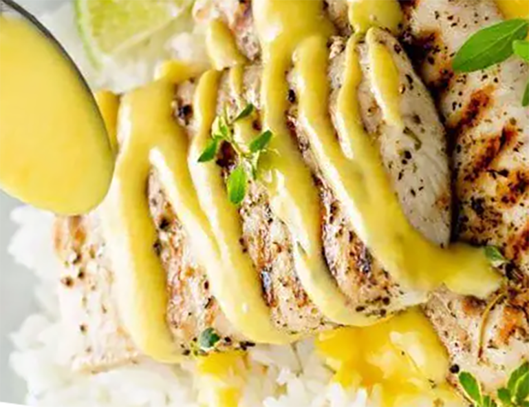 barbecued fish drizzled with amba sauce on a bed of rice