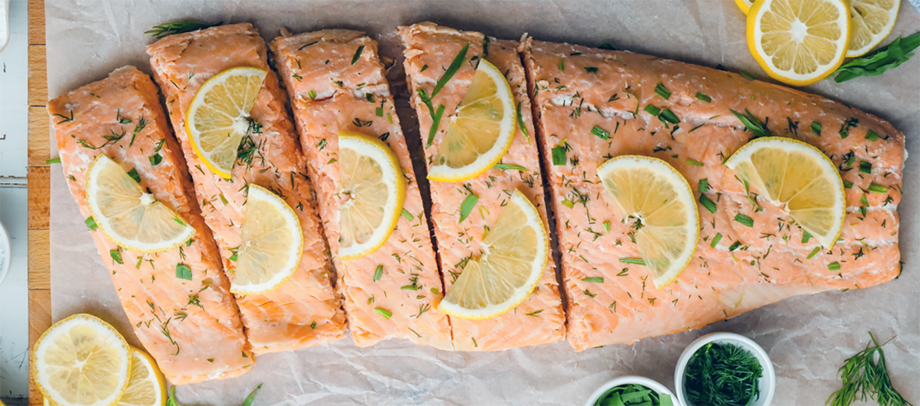 side of boiled salmon cut into steaks served with lemon slices