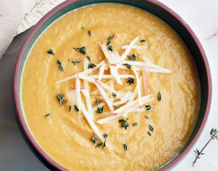 pureed carrot and turnip soup in a bowl garnished with grated turnip