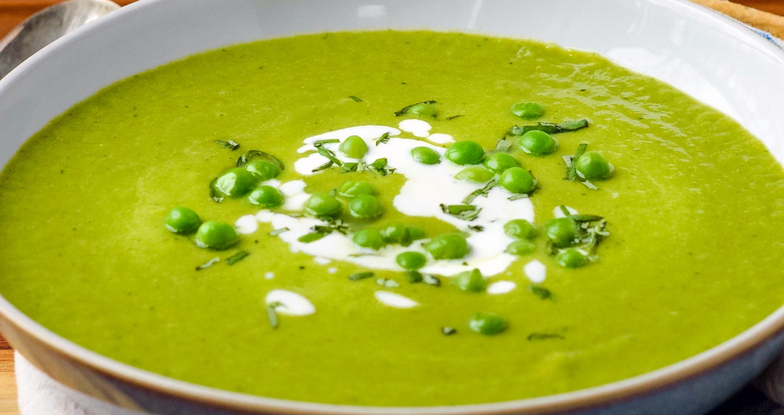 garden pea and parsley soup served garnished with creme fraiche and peas