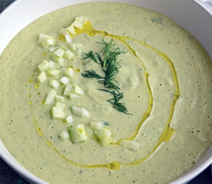 cucumber cream soup in a bowl garnished with diced cucumber, a swirl of olive oil and chopped dill