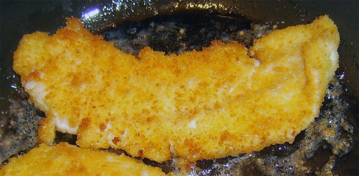 breaded whiting cooking in a frying pan