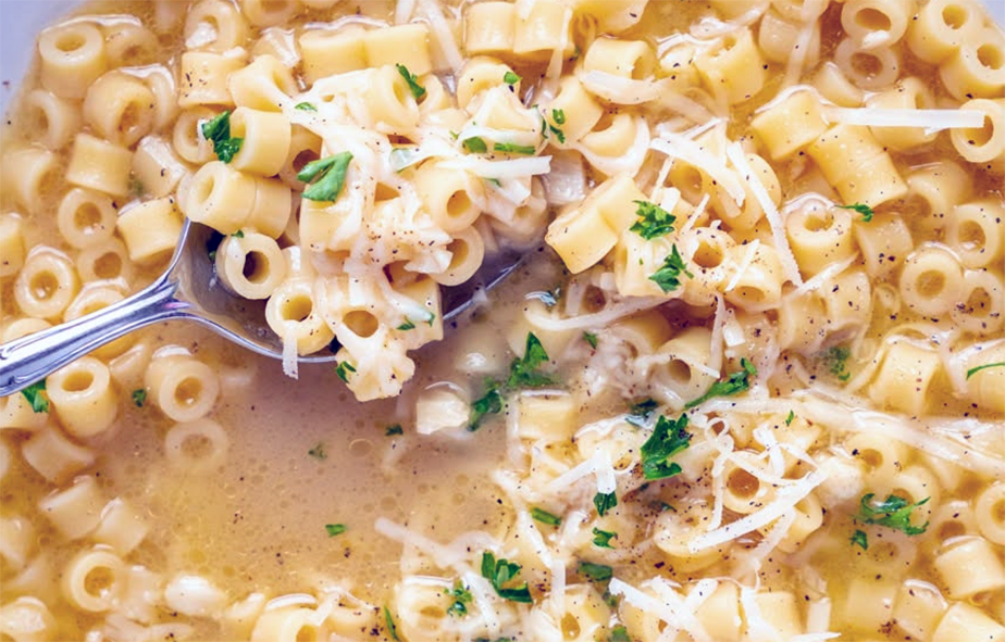 Macaroni soup served garnished with parmesan cheese and flat-leaf parsley