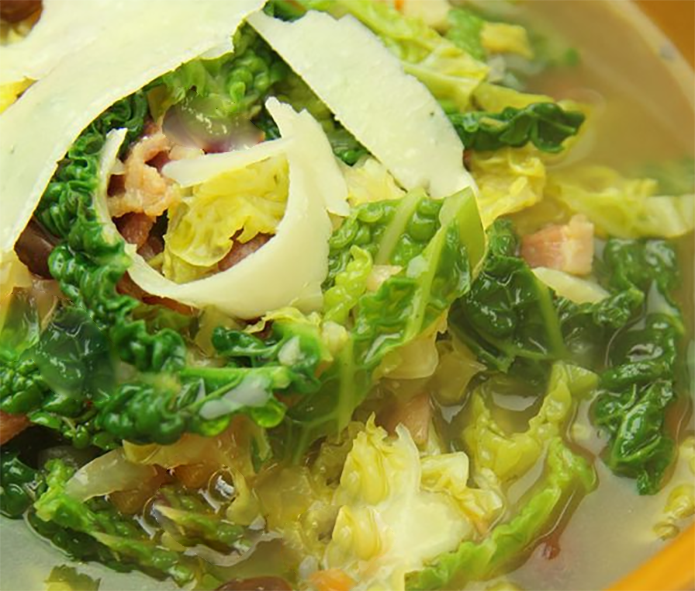 savoy cabbage soup in oatmeal stock served garnished with parmesan shavings