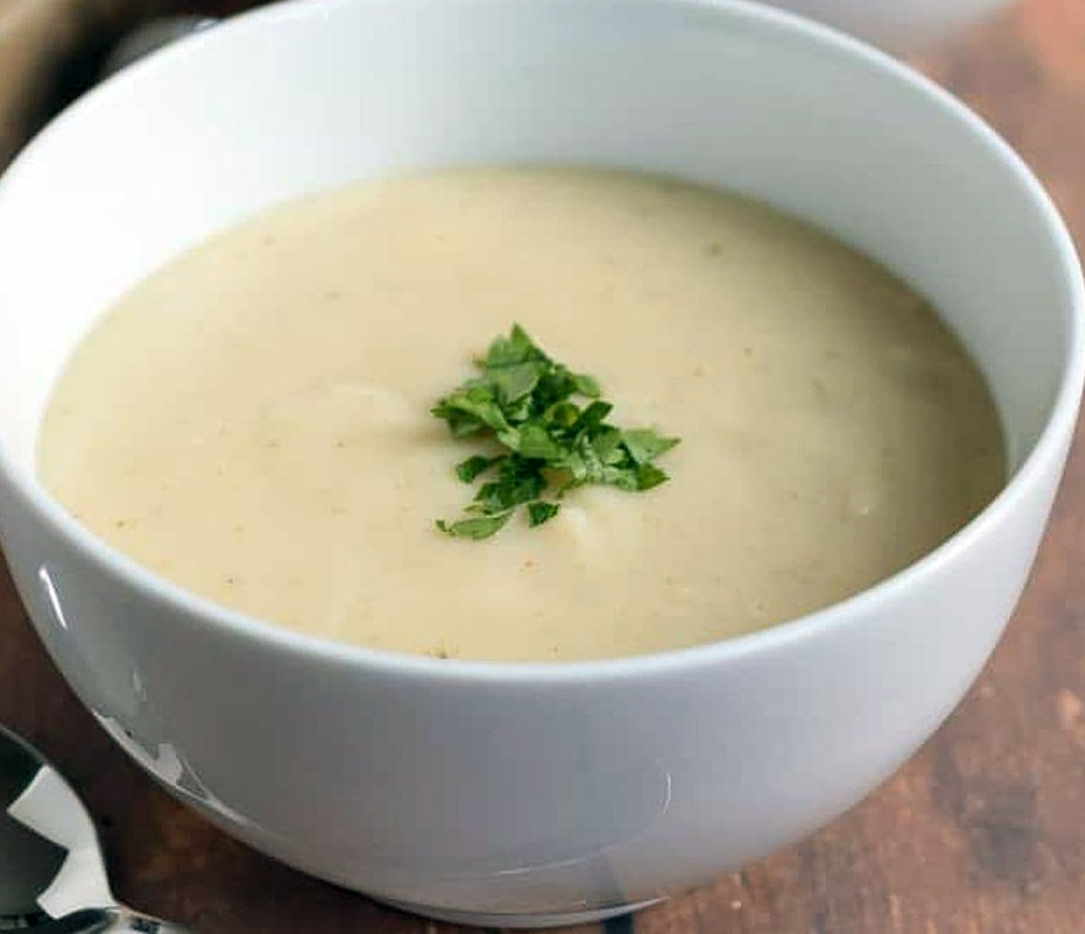 creamy parsnip soup garnished with parsley in a soup bowl
