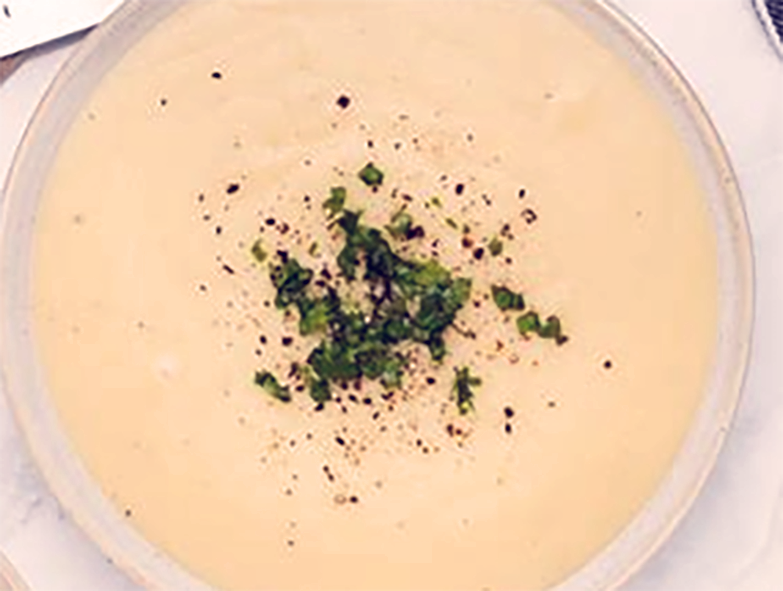 smooth potato soup in a soup bowl with herb garnish