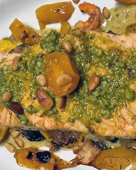Salmon with green sauce served on a bed of fried vegetables