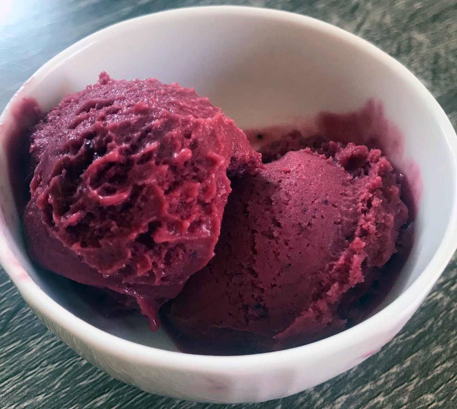 two scoops of bilberry sherbet in a white bowl