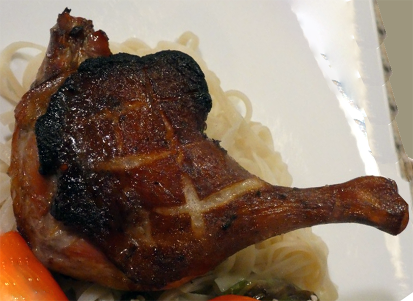 blackened duck leg on a plate with noodles