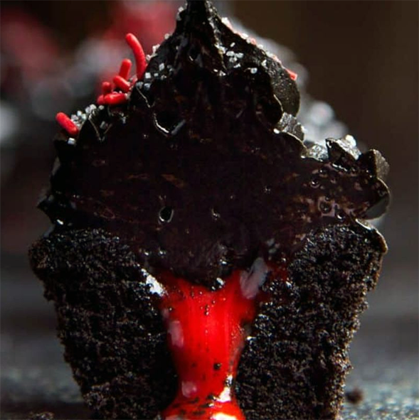 chocolate cupcake split open to reveal the red bleeding filling