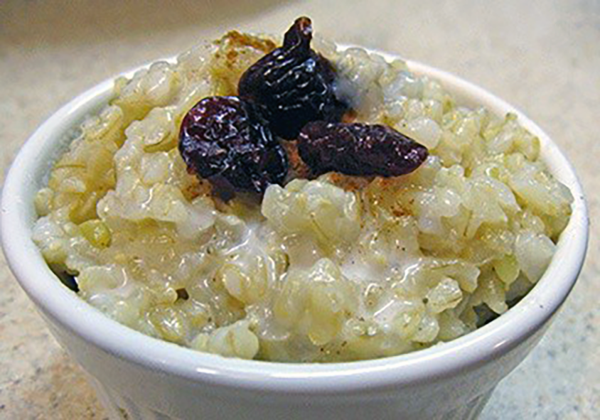 boiled rice pudding served in a bowl with a garnish of stewed fruit