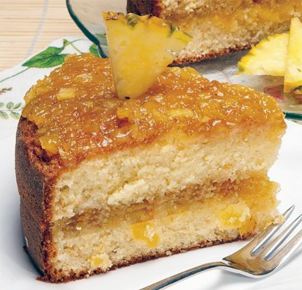 wedge of two layer sponge cake with pineapple and egg custard filling served garnished with some of the filling mixture and a pineapple wedge