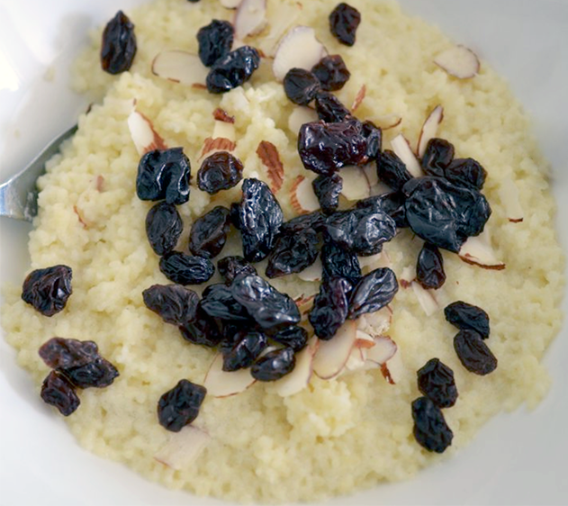 Breakfast couscous served in a bowl topped with raisins and slivered almonds