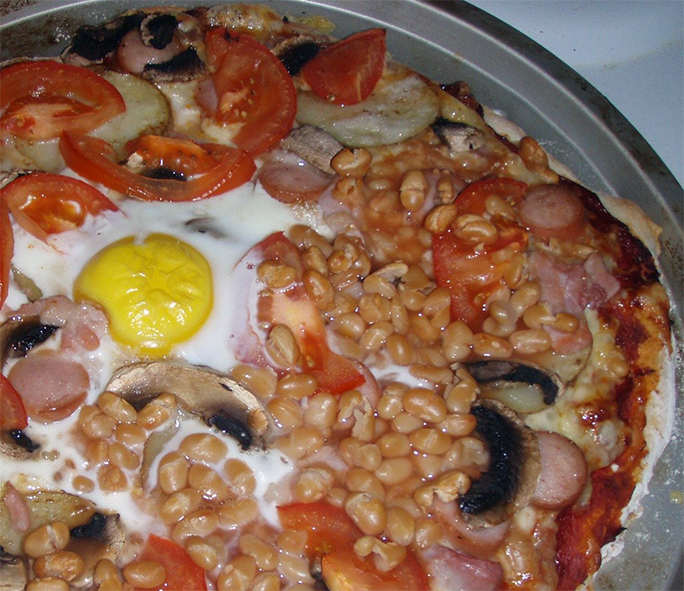 full English breakfast pizza on a metal pizza dish