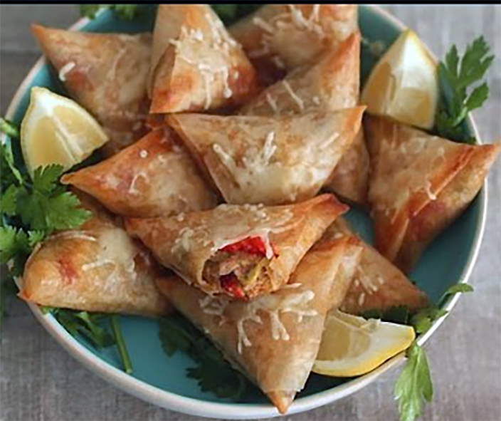 Algerian tuna turnovers arranged on a plate with lemon pices