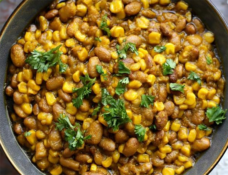 Cornchaff dish of maize and beans served in a bowl and garnished with curly parsley
