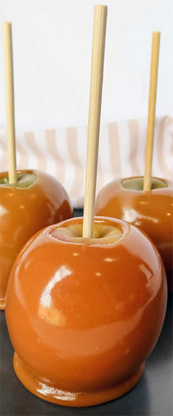 caramel marshmallow coated apple with a stick on a baking tray