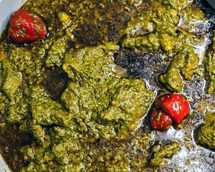 meat and cassava leaf stew garnished with hot chillies and served in a bowl