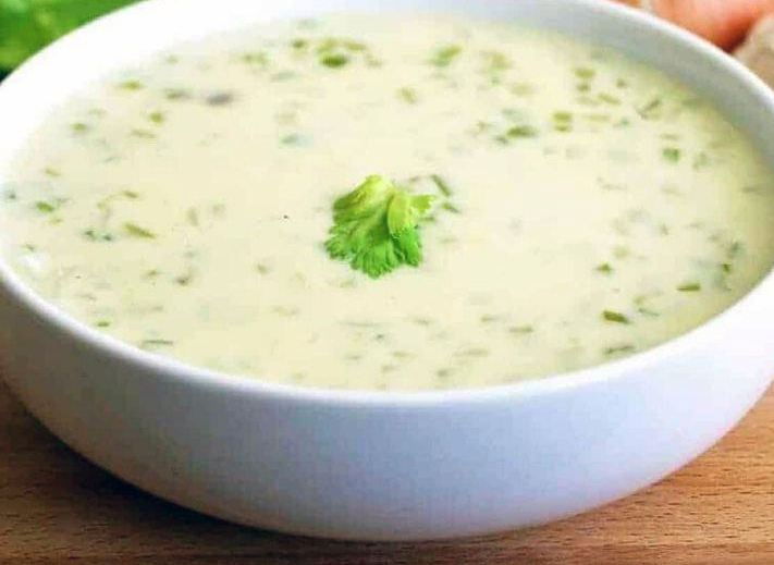 celery and onion cream sauce served in a white bowl with a sprig of celery leaves