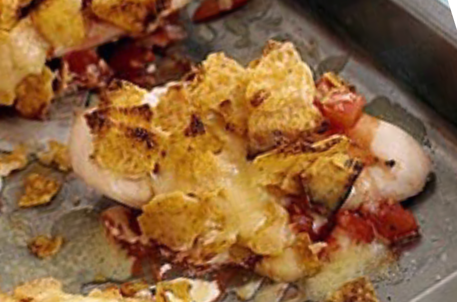 chicken breast baked with a topping of tortilla chips, sour cream, tomato salsa and cheese on a baking tray