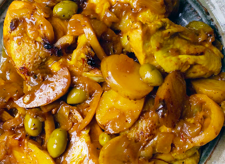 chicken fried with sliced potatoes, green olives and lemon in a spiced chicken stock base presented on a plate