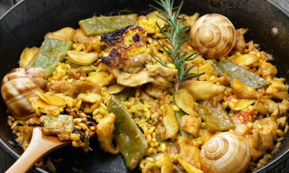 chicken and snail paella in a frying pan