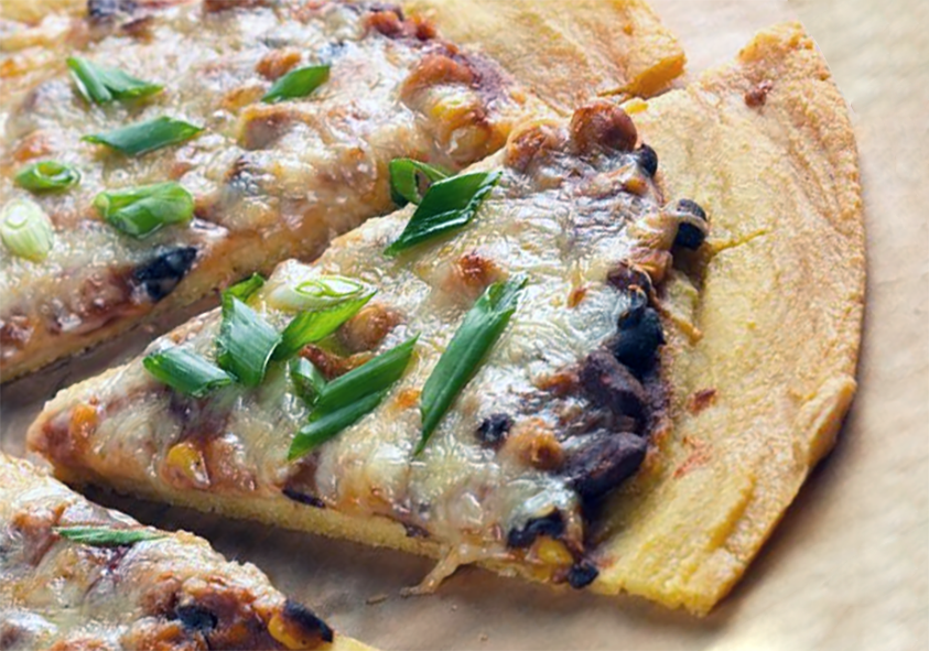 wedge of chii bean cornmeal pizza on a sheet of greaseproof paper garnished with spring onions