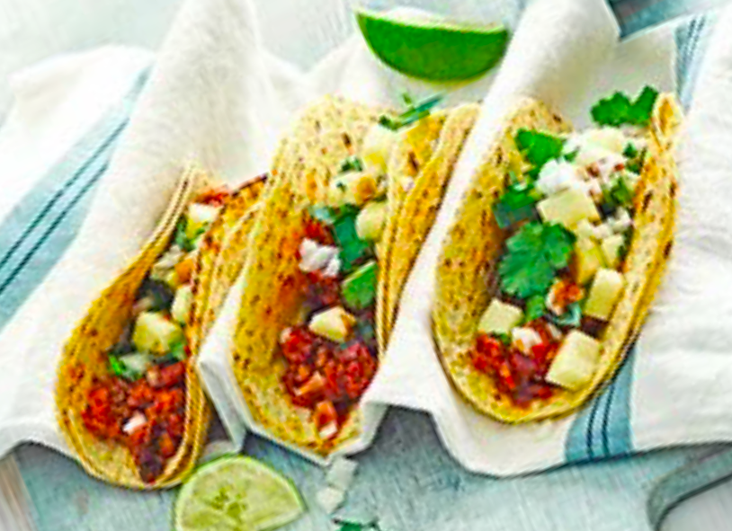 three pineapple salsa topped chipotle chicken tacos held in cloth napkins