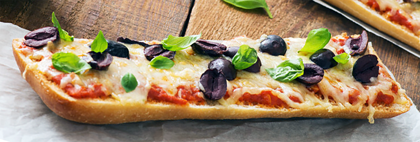 sliced ciabatta topped with tomato sauce, mozzarella cheese, black olives and basil leaves