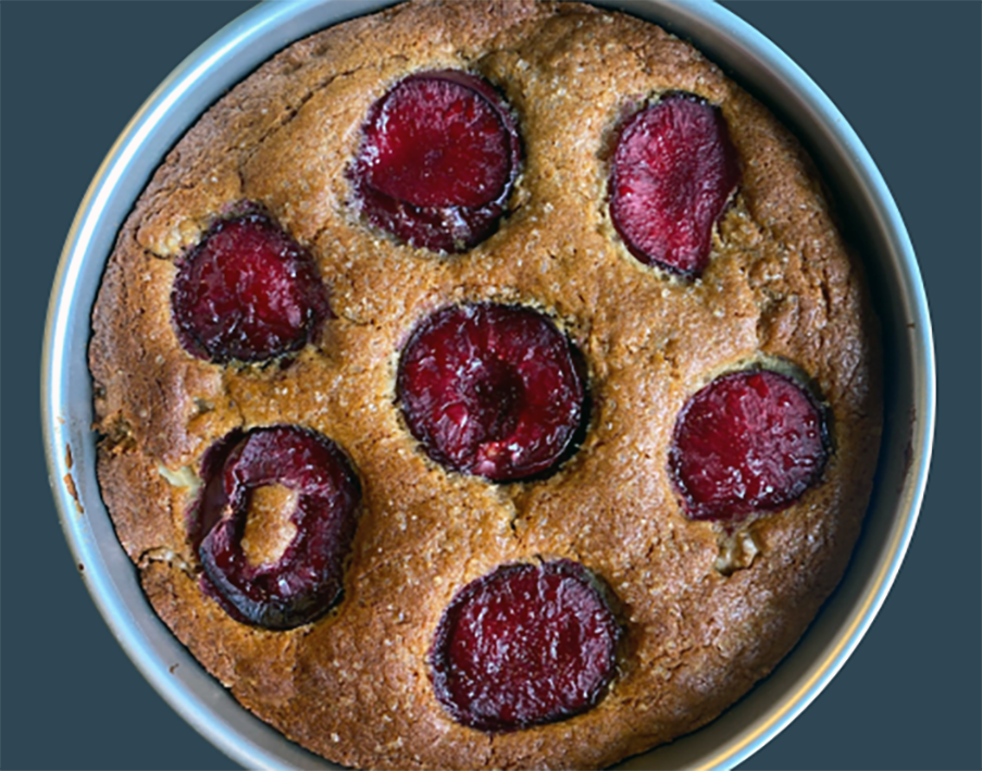 sponge with cobnuts in the batter baked in a circular cake tin with halved plums set in the top of the cake