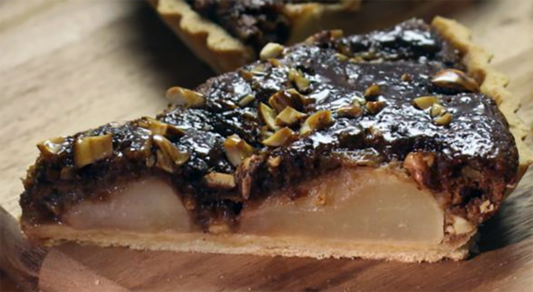 Slice of pear tart with a cobnut and sticky toffee topping on a chopping board