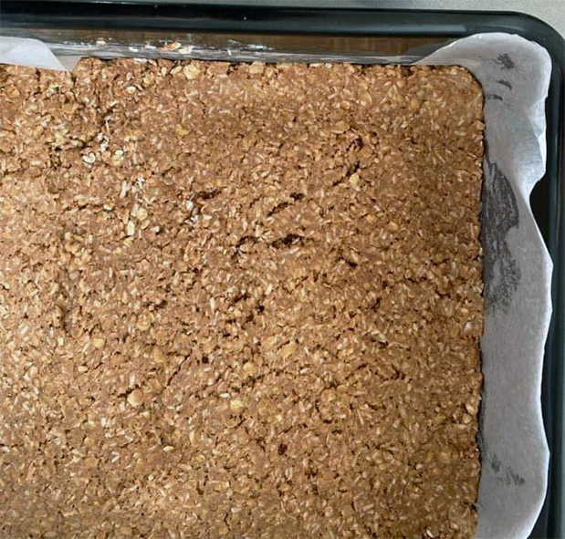 coconut candy pressed into the base of a paper lined baking tin