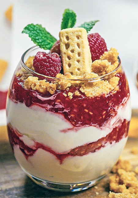 cranachan with raspberries and shortbread served in a glass with a shortbread finger and mint garnish