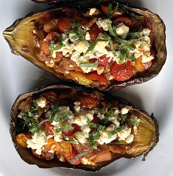 aubergine halves cooked with onions and tomatoes on a plate
