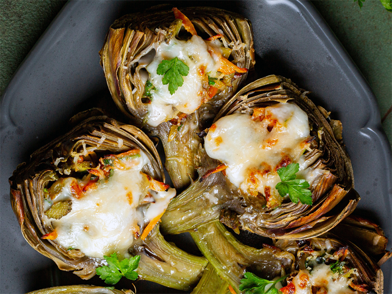 stuffed arthchokes served halved and topped with white sauce 