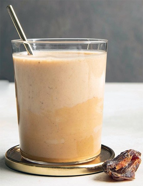 date yoghurt smoothie in a glass with a straw next to a date