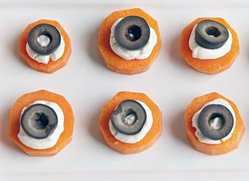 edible carrot eyes with cream cheese and olives on a white plate