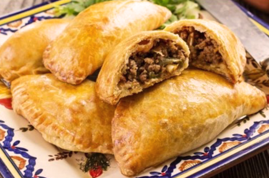 baked minced beef empanadas served on a plate with one split open to reveal the filling