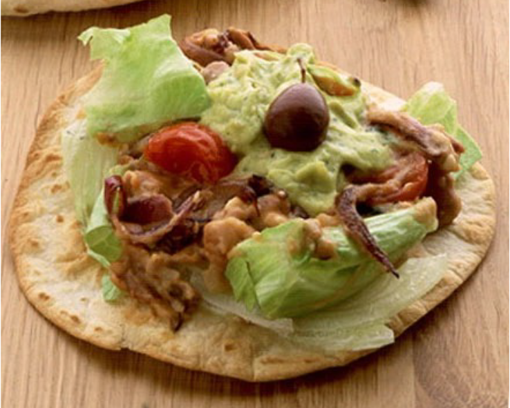 taco shell topped with refried beans, cherry tomatoes, feta cheese, lettuce and guacamole