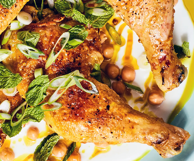 whole roast chicken leg in a spicy yoghurt dressing garnished with nuts and mint