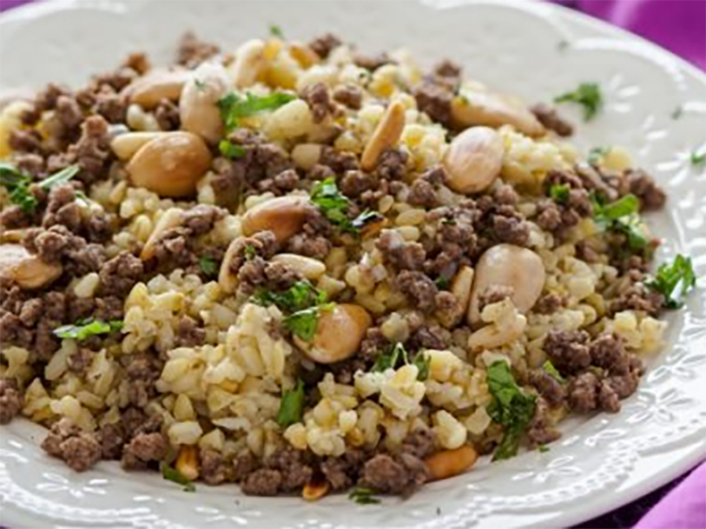 palestinian freekeh mfalfaleh, pilaf topped with meat stuffing served on a plate