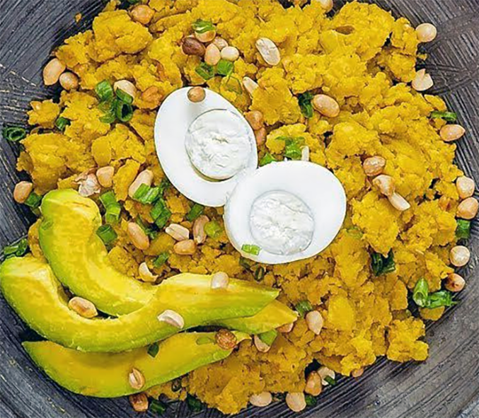 Ghanaian plantain etor served topped with hard-boiled egg quarters, avocado slices and peanuts