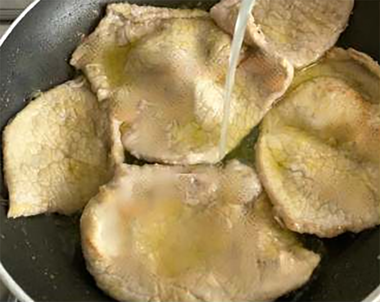 thinly-sliced veal with lemon juice in a frying pan