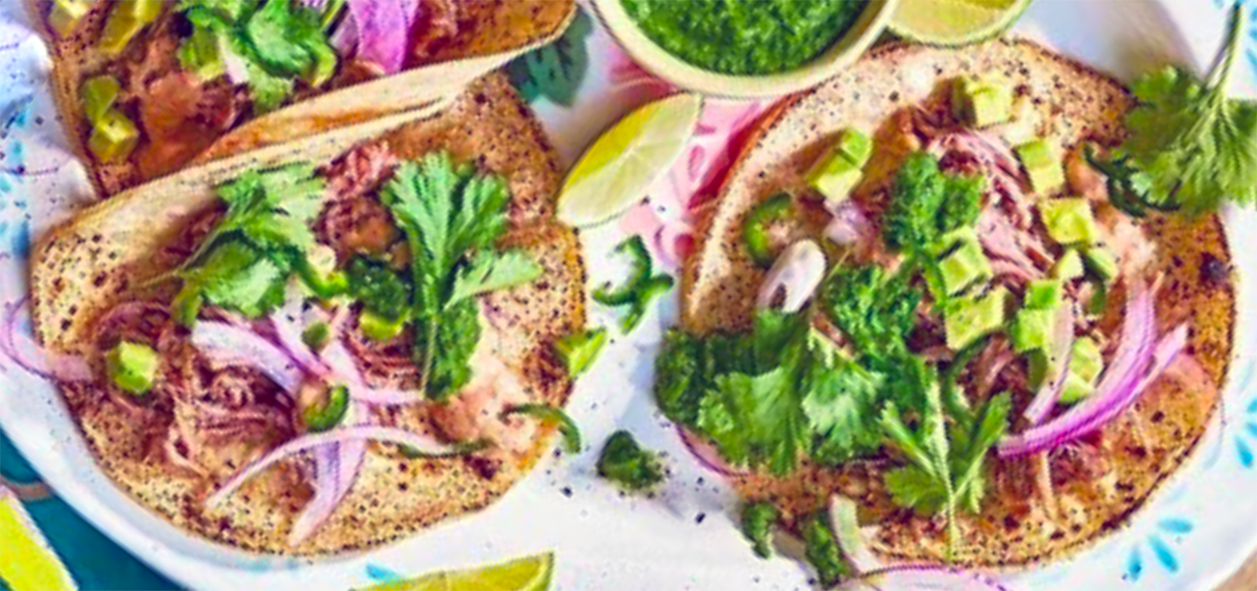 two goat tacos in a plate with a bowl of green sauce