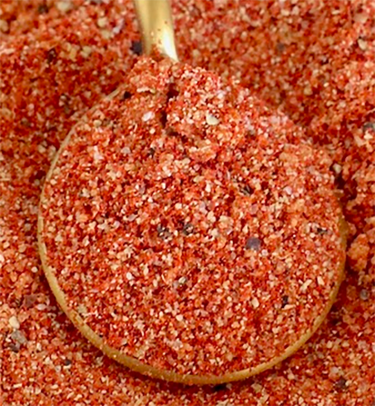gochugaru seasoning blend on a spoon against a background of the spice blend